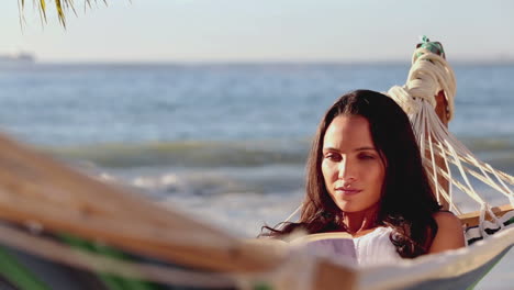 brunette woman reading a book on a hammock