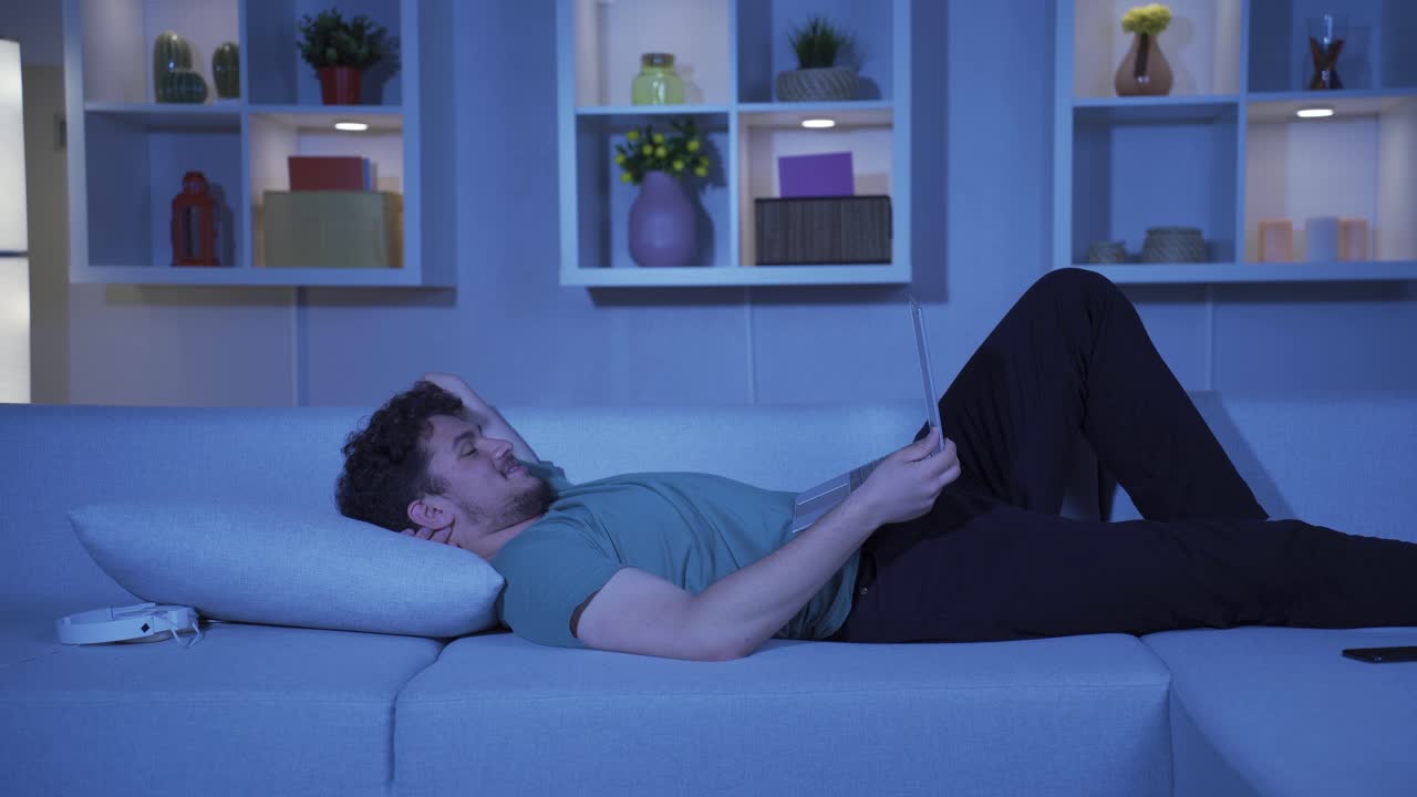 집에서 밤에 노트북에서 영화를 보는 남자.