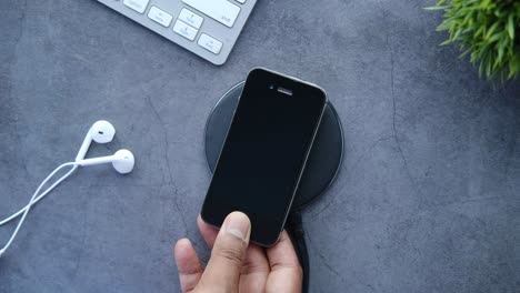 wireless charging smartphone with earbuds and keyboard on a desk