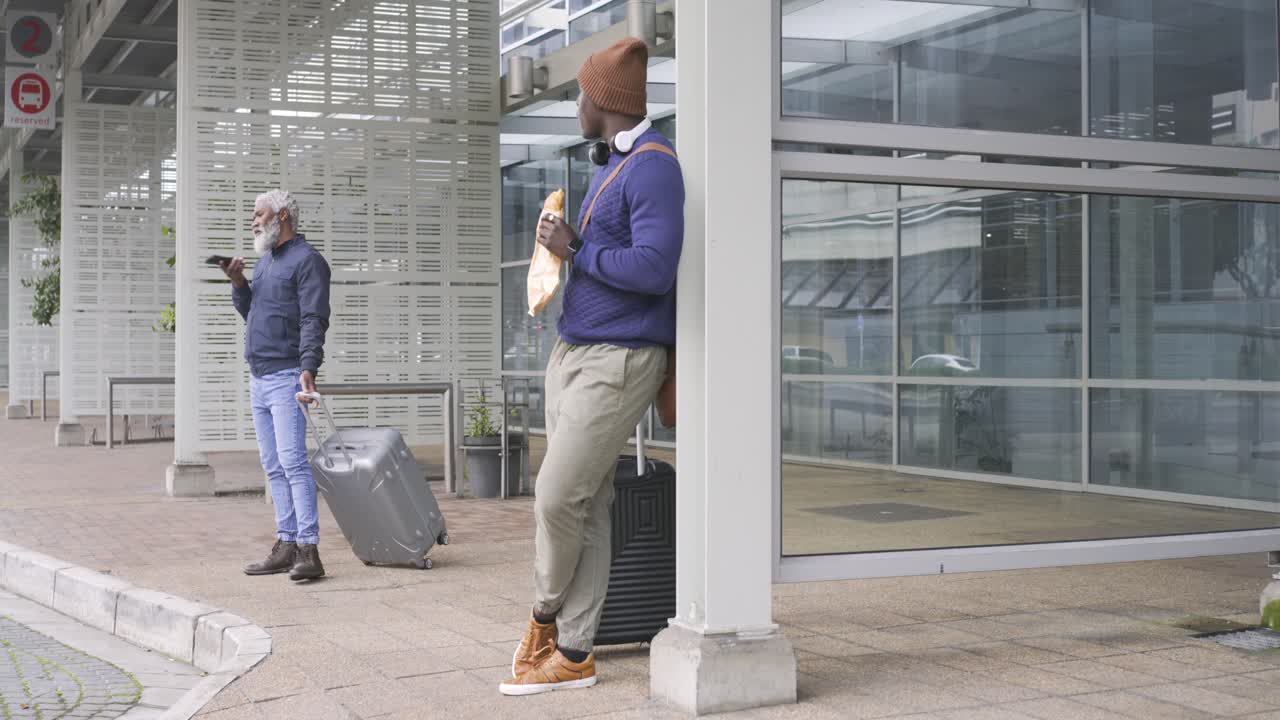 Uomo afroamericano che arriva al marciapiede mangiando un panino e osservando un viaggiatore che passa, con spazio per il testo.