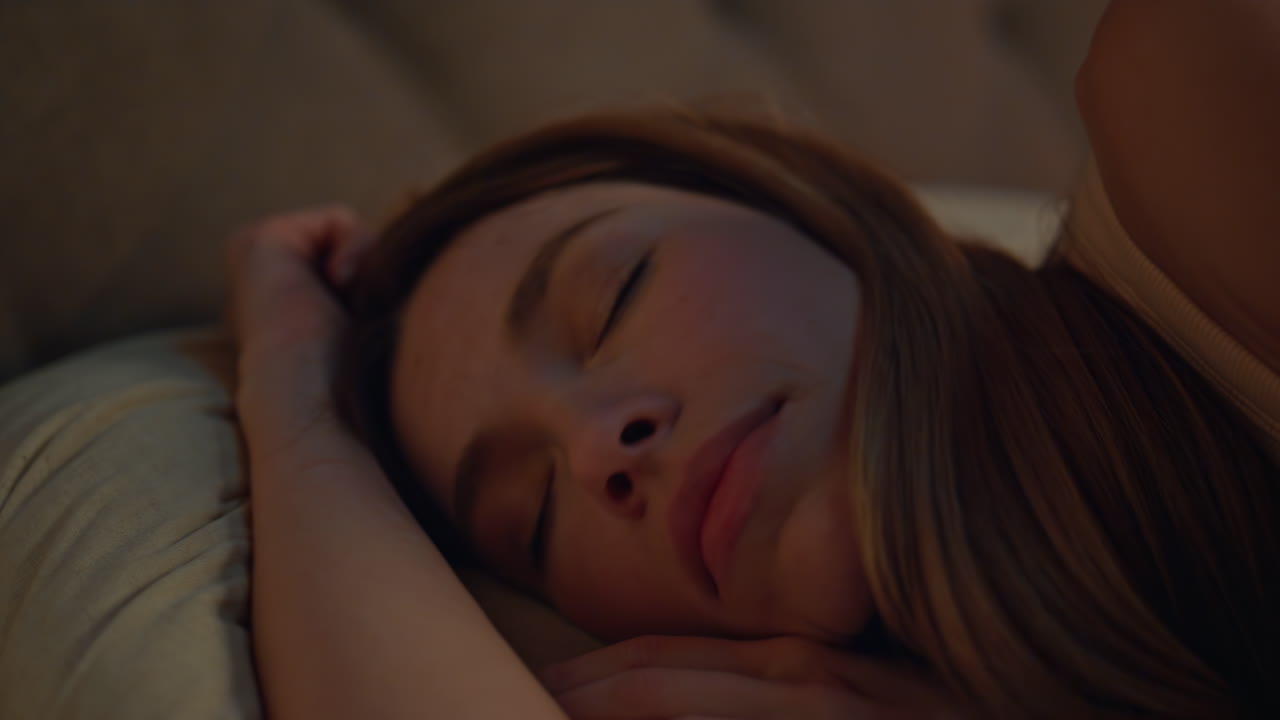 Closeup woman sleeping pillows dark apartment. Relaxed attractive girl lying bed