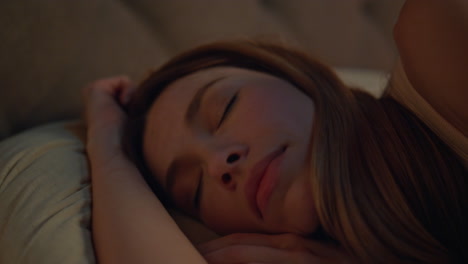 closeup woman sleeping pillows dark apartment. relaxed attractive girl lying bed
