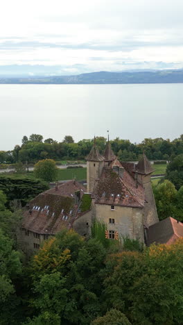 vertical, aerial: vaumarcus castle and lake neuchatel during the day in canton of neuchatel, switzerland, push in drone shot
