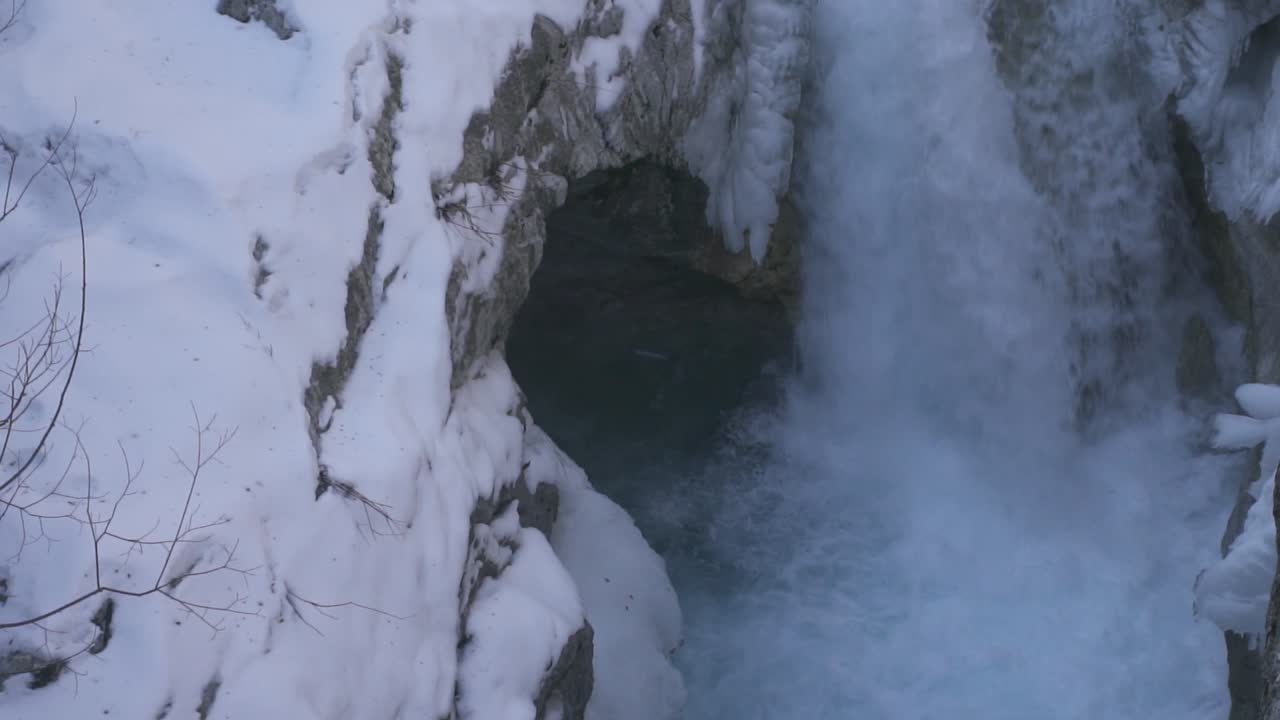 cascada rodeada de rocas nevadas congeladas salpicando y espumando, paisaje isleño