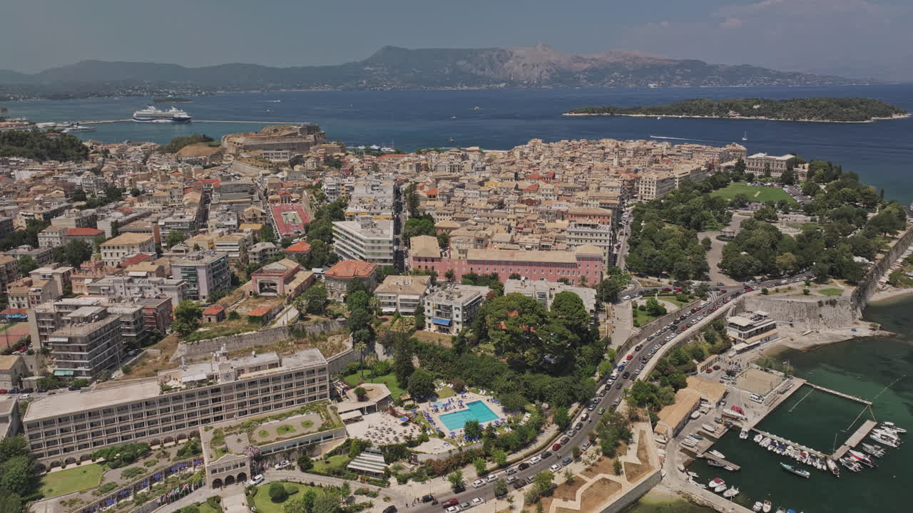 Corfù Grecia Aerea v6 sorvolo della baia di Garitsa che cattura il porto turistico, il paesaggio urbano di un'incantevole isola costiera e le montagne in lontananza attraverso il mare - Ripreso con Mavic 3 Pro Cine - 16 luglio 2024