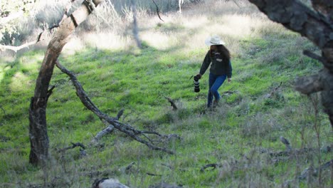 mujer fotógrafa de rancho vagando por el bosque en busca de vida silvestre