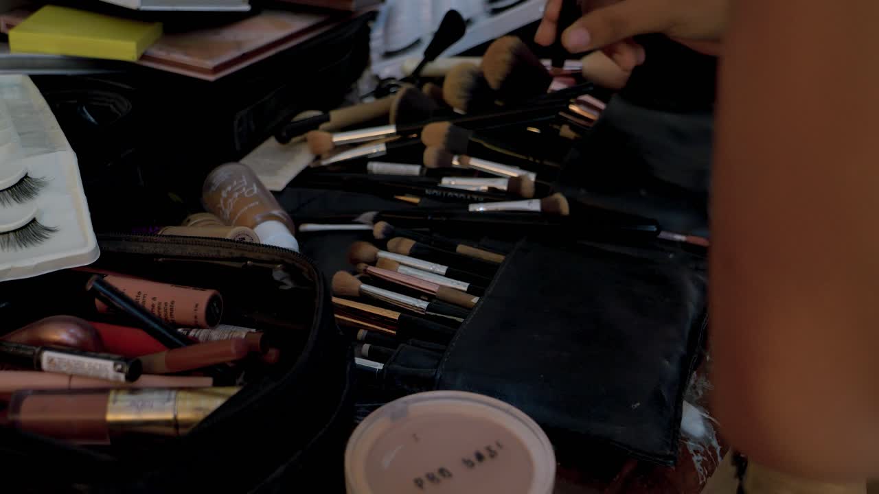 Slow motion shot of a makeup artist selecting from a large collection of brushes