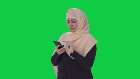 mujer musulmana usando una pantalla verde de teléfono