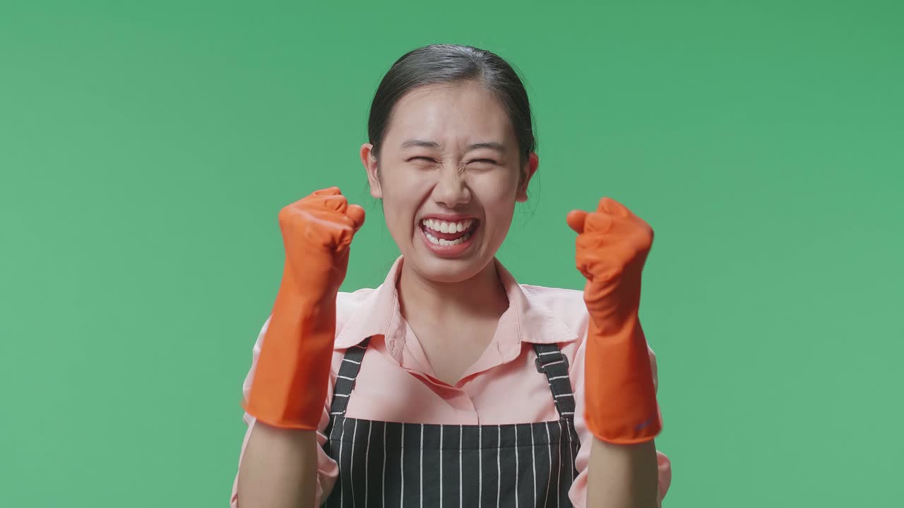 초록색 스크린 스튜디오에 서서 축하하는 아프론을 입은 행복한 아시아 여성 집주인의 클로즈업