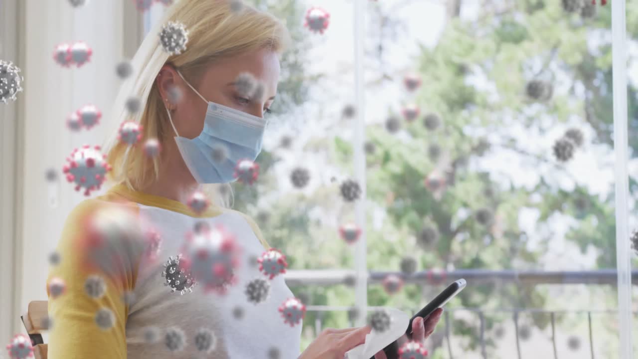 animación de células de covid 19 sobre una mujer rubia caucásica que usa una máscara facial usando un teléfono inteligente