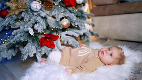 charming baby boy lies under the christmas tree. first family christmas celebration with a child.