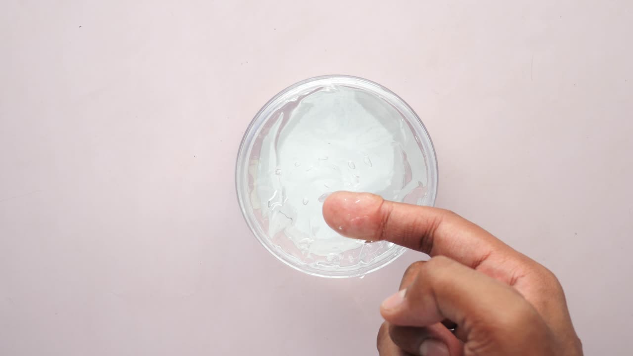la mano sostiene un frasco de gel para el cabello