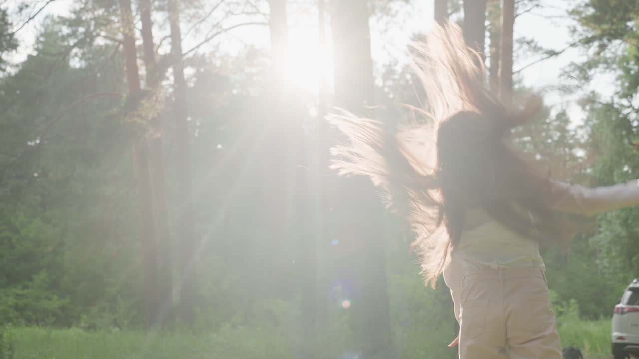 Picnic girl performing acrobatic movement on mat in sunny forest clearing with golden sun beam shining through trees, creating sense of freedom, and harmony during joyful summer outdoor moment