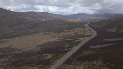 lonely car drives on remote road in airy highlands - aerial