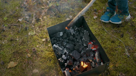 Close-up-the-plan-to-burn-sticks-on-the-fire-and-play-with-fire-in-the-forest.-Children-play-with-burning-sticks-in-the-woods