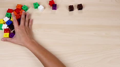 las manos organizan cubos coloridos en una mesa de madera