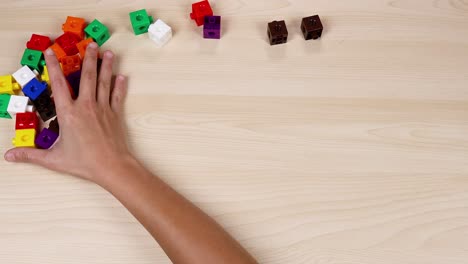 hands organize colorful cubes on a wooden table