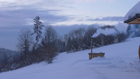 Smoking-furnace-in-winter-next-to-a-mountain-cabin,-Poland,-wide-shot