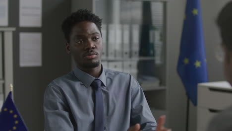 african american consular officer explaining eu immigration rules to applicant