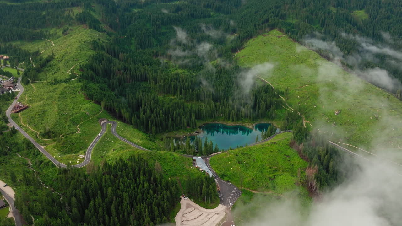 Lago di Carezza alpine lake in Dolomites in south Tyrol with Latemar mountain range in background, Drone shot