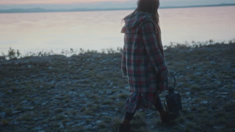 girl holding lantern as wandering along lakeside in the evening