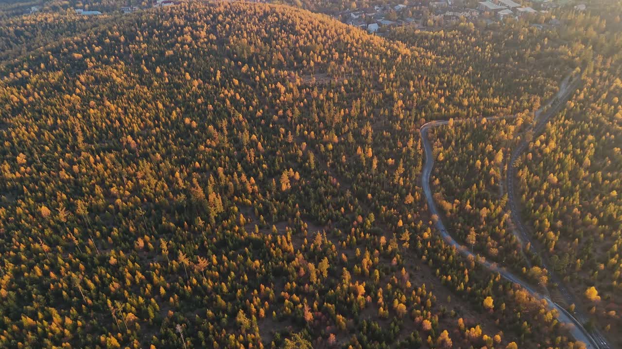 A drone shot transitions from a top-down view to a horizontal perspective, showcasing vibrant autumn forests, Nizke Tratry range, and Slovak town Smokovec under warm sunlight. Location: Slovakia