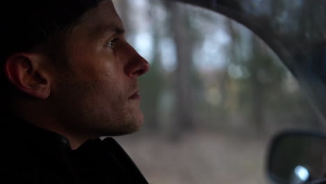 profile of the handsome face of a young man as he drives through the forest on a special trip