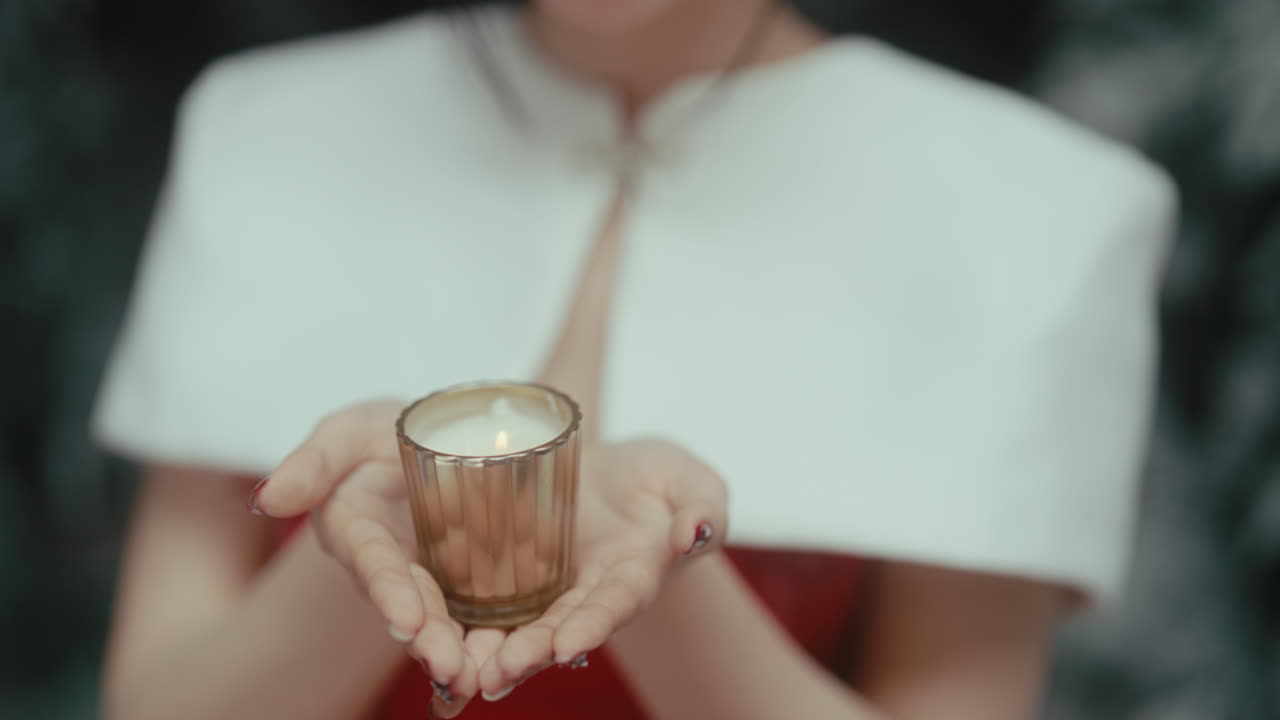 Woman holding a candle in soft focus, offering warmth and serenity with a gentle smile