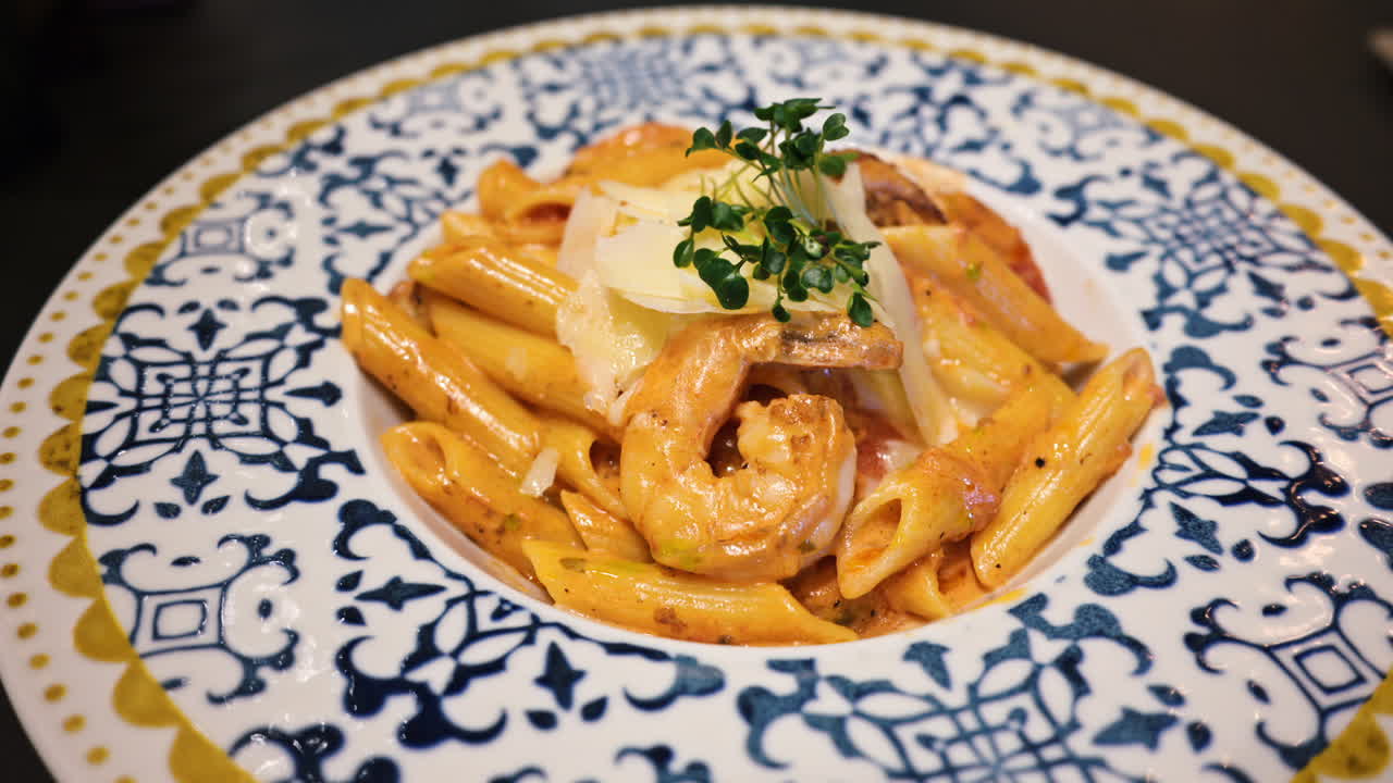 Penne seafood pasta with shrimps and parmesan cheese in a beautiful ceramic plate