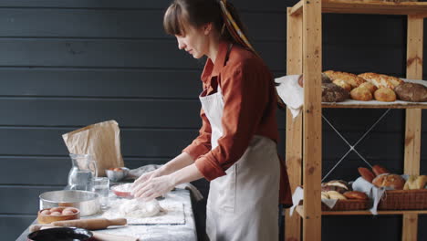 female bakery chef kneading dough on kitchen table