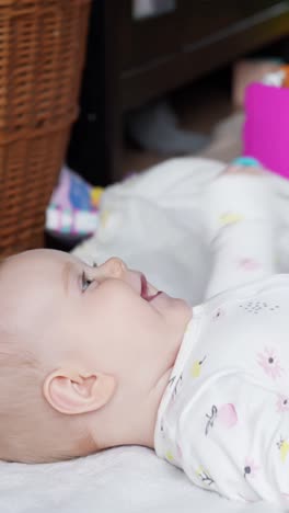baby girl touching toy with hands while laying on back, focused expression in warm home setting