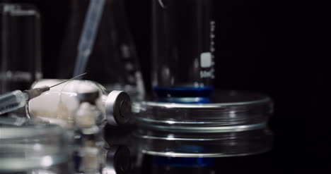 equipo de laboratorio: jeringas y tubos de ensayo de medicamentos y matraces girando sobre fondo negro 2