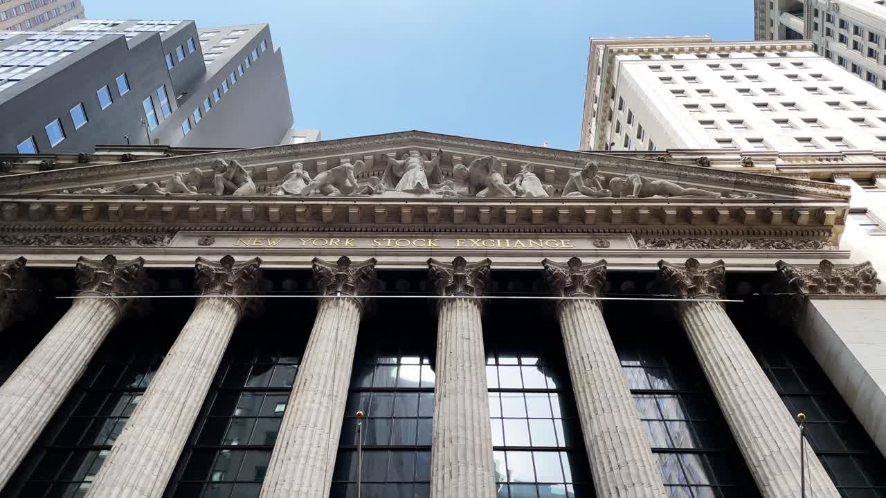 Panning from top to bottom at the New York Stock Exchange NYSE with US flags on Wall Street in Manhattan