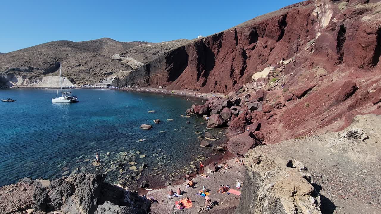 Scenic Red Beach of Santorini with Sailboat and Bathers