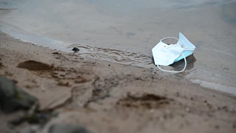 máscara facial sucia descartada flotando en el lado del río en un día nublado- toma estática