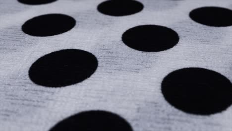 spotted fabric cloth close up shot. black dots on white background, monochrome pattern.