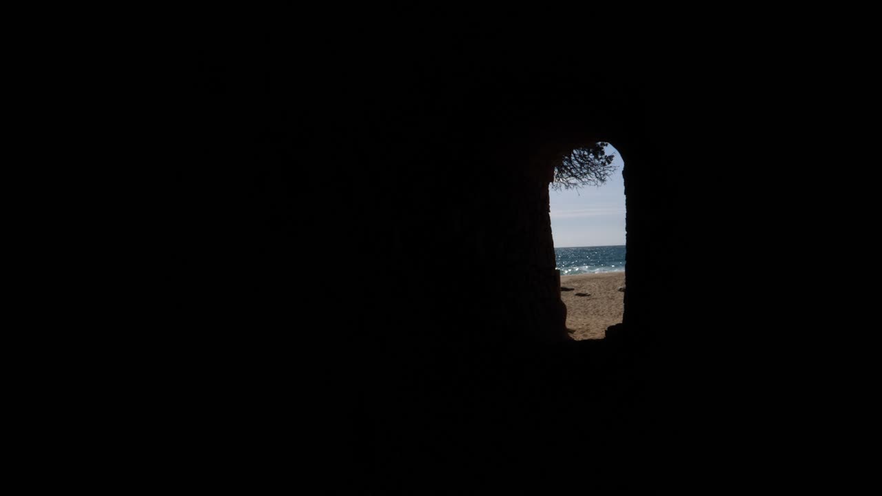 vista abstracta de la playa y el océano a través de una cueva oscura que se abre