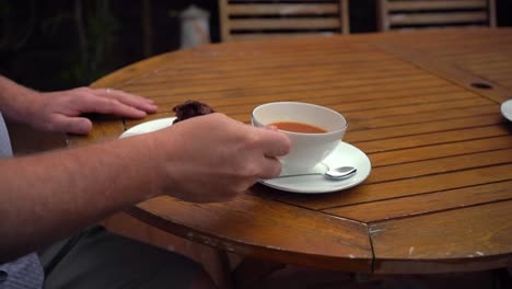 bebiendo una taza de té inglés de una taza de porcelana blanca relajándose en el jardín con un muffin de chocolate