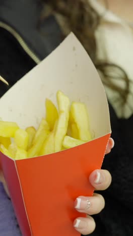 eating french fries from a paper cone
