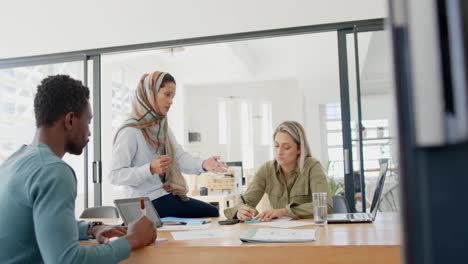 busy diverse business people discussing work at table with laptop in slow motion