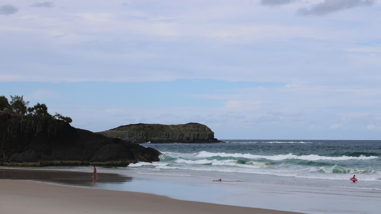 surfistas y olas en una pintoresca playa rocosa