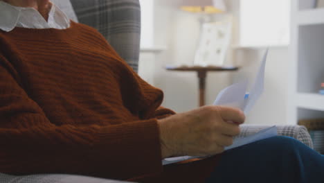 close up of senior woman at home looking at energy bill during cost of living energy crisis