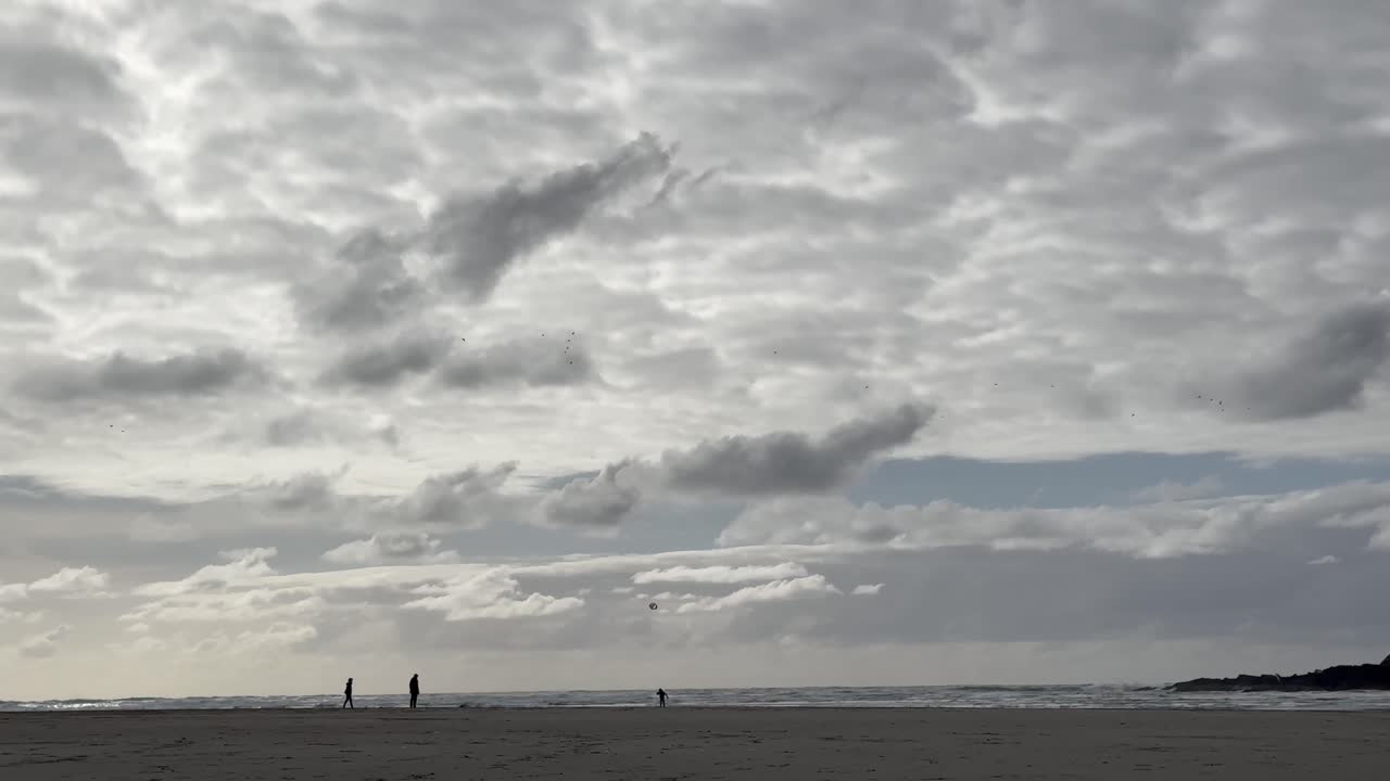 오리건 해안 위의 구름진 하늘과 오리건 해변의 가족 실루, 미국