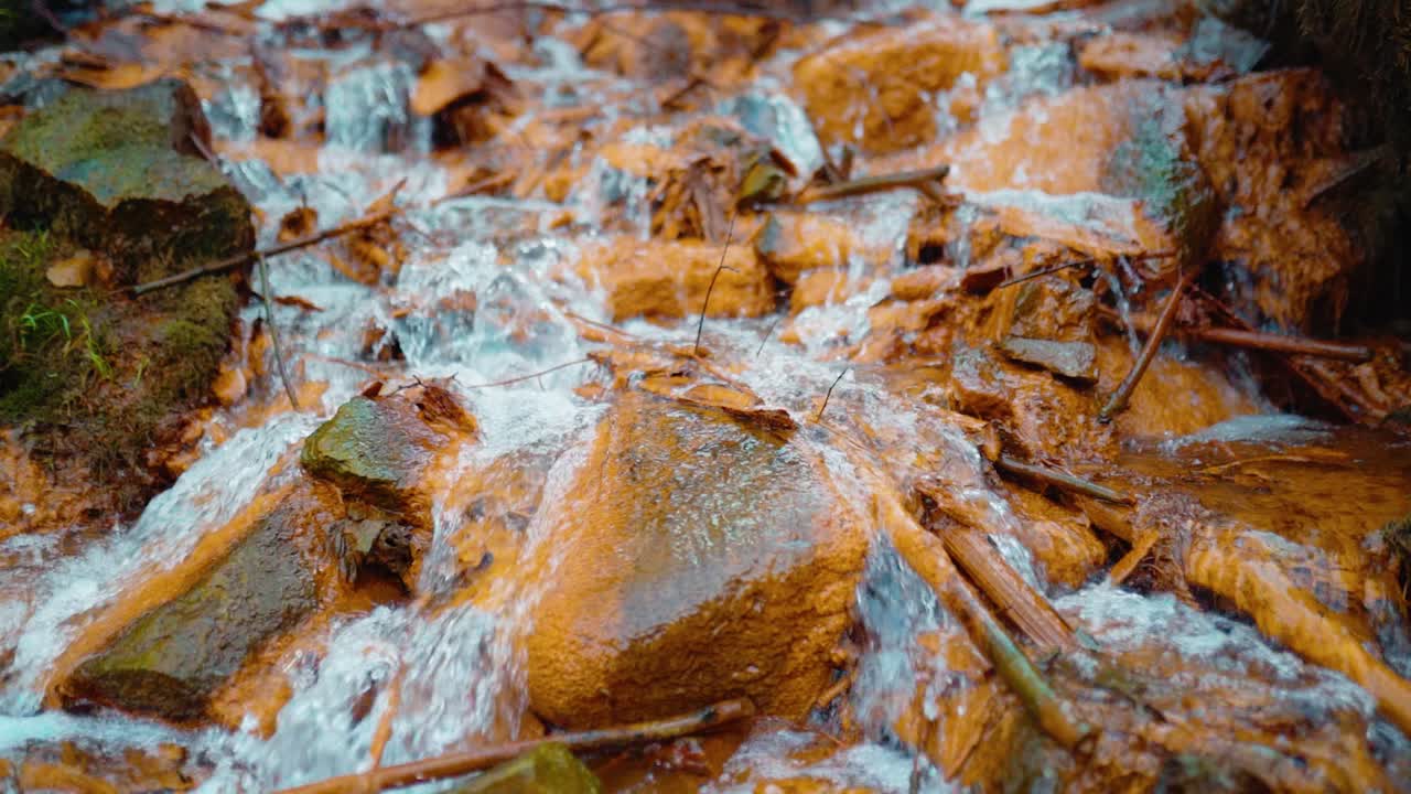 Slow motion of beautiful iron-containing sulfur spring waterfall in forest.