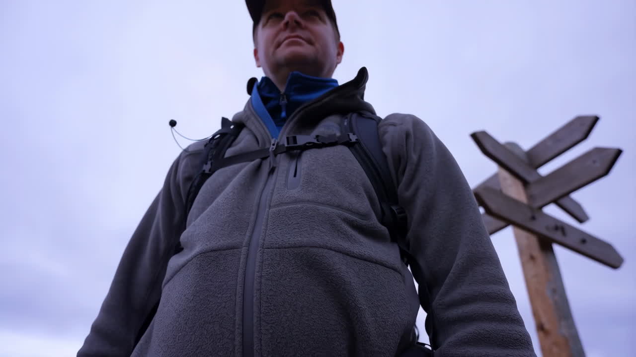 Hiker next to a wooden direction sign