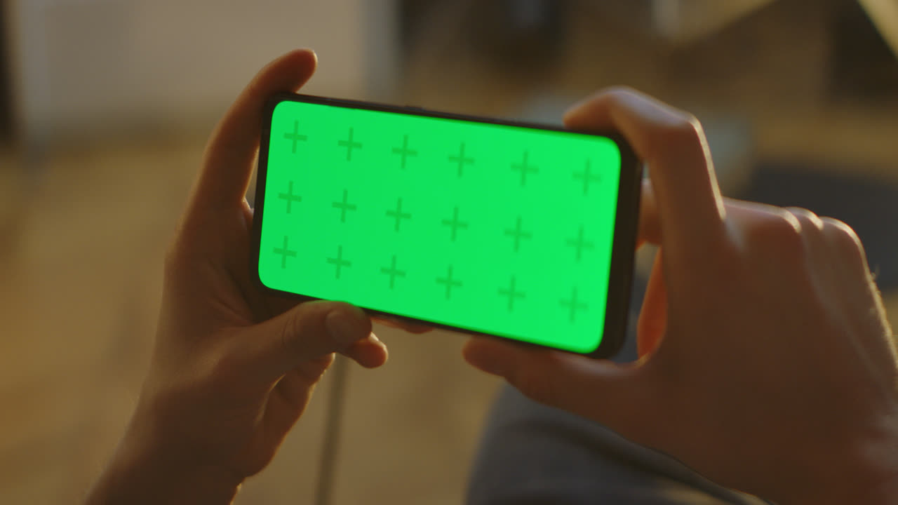 초록색 화면의 스마트폰을 들고 있는 사람