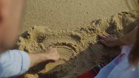 Young-couple-drawing-heart-on-sand