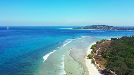 aerial of the beautiful blue waters and lush green flora on the tropical island of bali with a ship far in the horizon