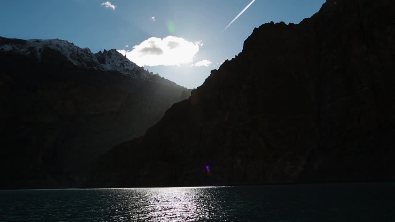 rayos de sol provenientes de nubes blancas y cielo azul sobre las altas montañas creando una vista majestuosa del lago