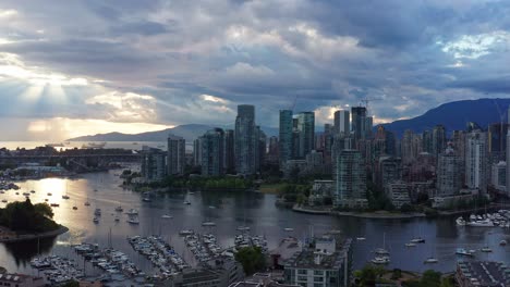 Moody-Puesta-De-Sol-Con-Rayos-De-Sol-Que-Alcanzan-Su-Punto-Máximo-Entre-Las-Nubes---Toma-Aérea-De-Drones-Sobre-El-Puerto-Deportivo-De-Vancouver